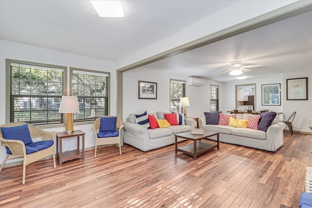 living room with a wall mounted air conditioner, light wood-type flooring, and ceiling fan