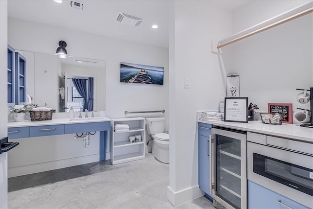 bathroom featuring toilet, vanity, concrete floors, and wine cooler