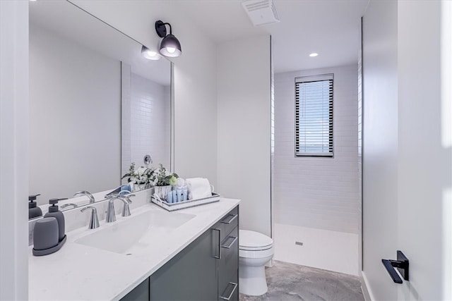 bathroom featuring vanity, toilet, and a tile shower