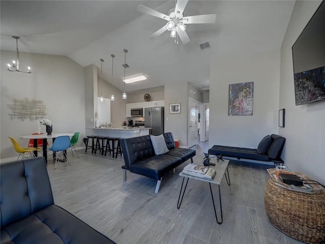 living room with light wood-type flooring, high vaulted ceiling, visible vents, and ceiling fan with notable chandelier