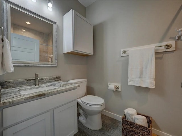 bathroom with wood finished floors, vanity, toilet, and baseboards