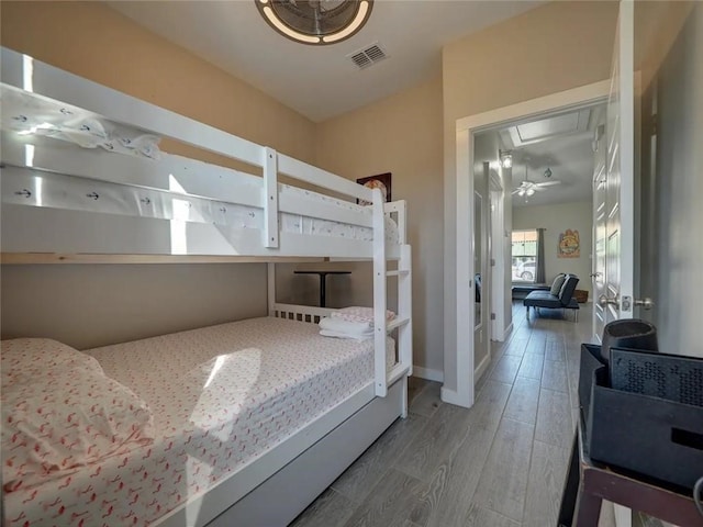 bedroom featuring baseboards, attic access, visible vents, and wood finished floors