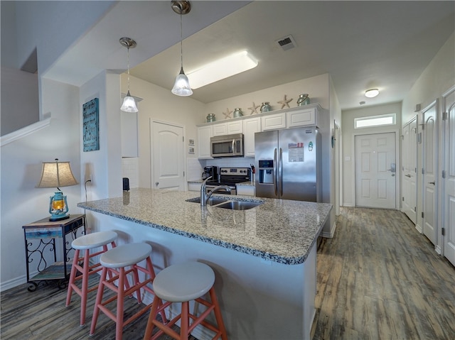 kitchen with a kitchen bar, hanging light fixtures, light stone countertops, white cabinetry, and appliances with stainless steel finishes