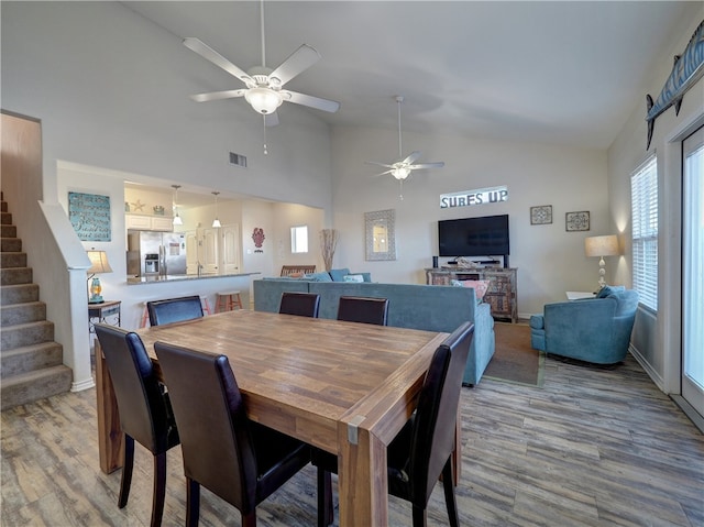 dining area featuring ceiling fan, wood-type flooring, and high vaulted ceiling