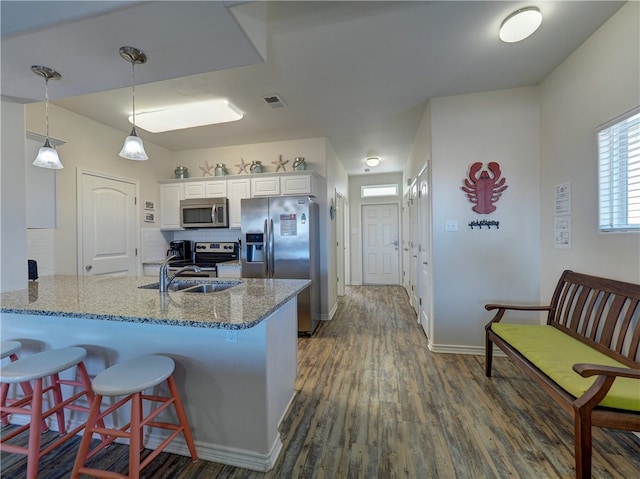 kitchen featuring dark wood-type flooring, kitchen peninsula, sink, white cabinetry, and appliances with stainless steel finishes