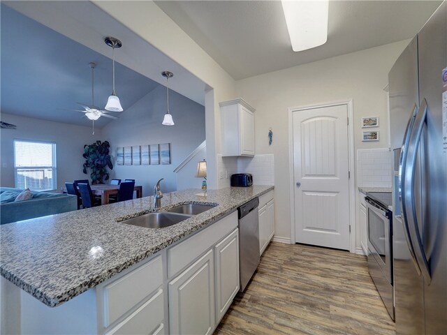 kitchen with white cabinetry, sink, kitchen peninsula, appliances with stainless steel finishes, and light hardwood / wood-style flooring