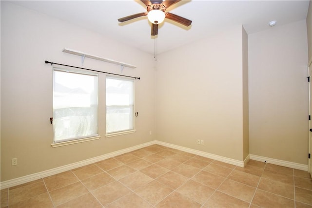 spare room with a ceiling fan and baseboards