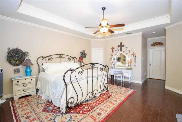 bedroom with a tray ceiling, wood finished floors, ornamental molding, baseboards, and ceiling fan