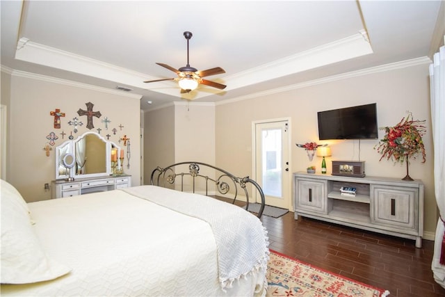 bedroom with a tray ceiling, wood finished floors, ornamental molding, and a ceiling fan