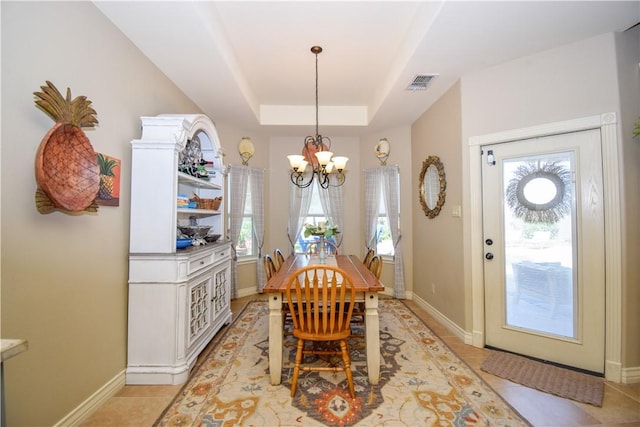 dining space featuring a chandelier, baseboards, light tile patterned floors, and a tray ceiling