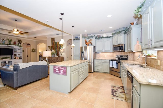 kitchen with appliances with stainless steel finishes, a sink, open floor plan, crown molding, and decorative backsplash