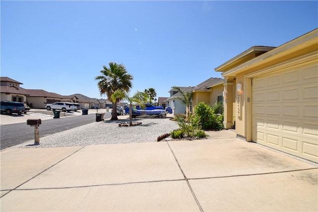 view of yard featuring a residential view, concrete driveway, and a garage