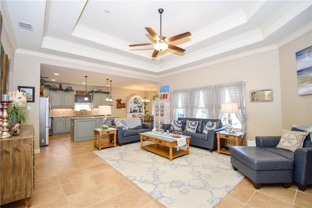 living area with a tray ceiling, ceiling fan, crown molding, and light tile patterned flooring