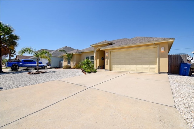 view of front facade with driveway, stucco siding, a garage, and fence