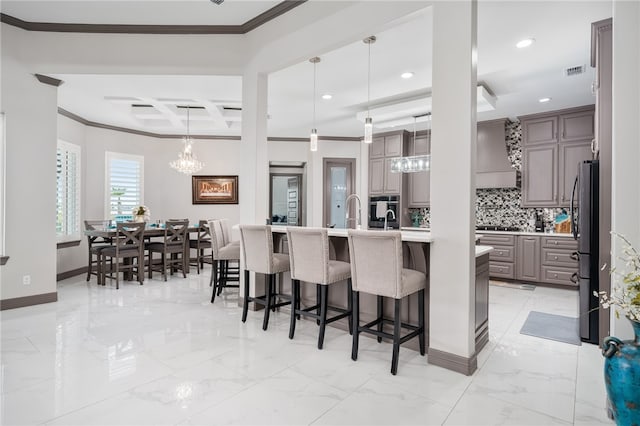 kitchen featuring stainless steel appliances, a kitchen bar, backsplash, crown molding, and pendant lighting