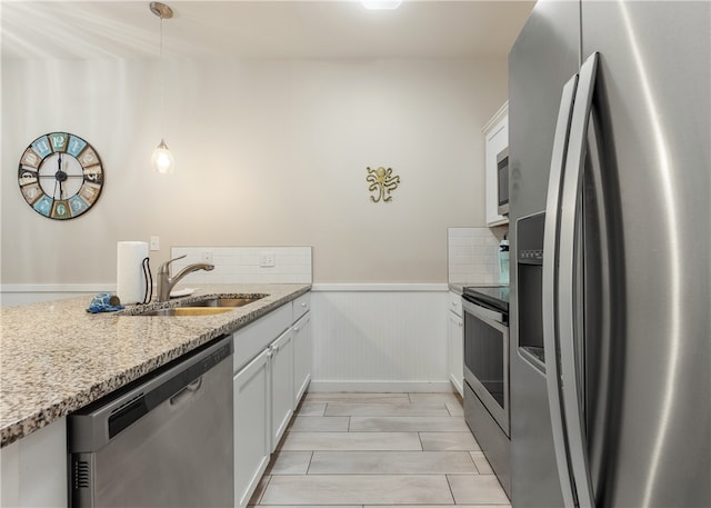 kitchen featuring appliances with stainless steel finishes, decorative light fixtures, white cabinetry, and sink