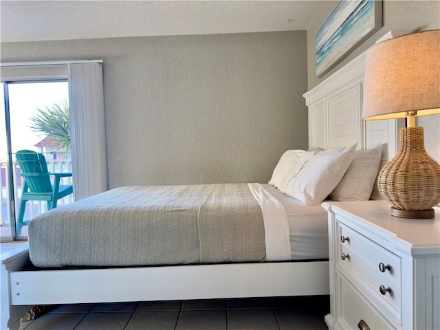 bedroom with a textured wall and dark tile patterned floors