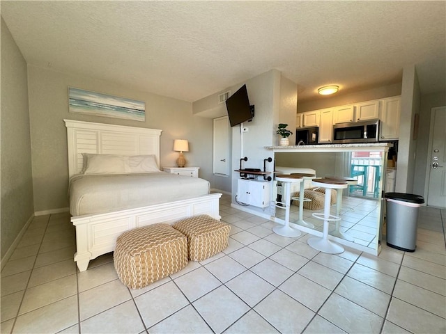 bedroom with light tile patterned floors, baseboards, and a textured ceiling