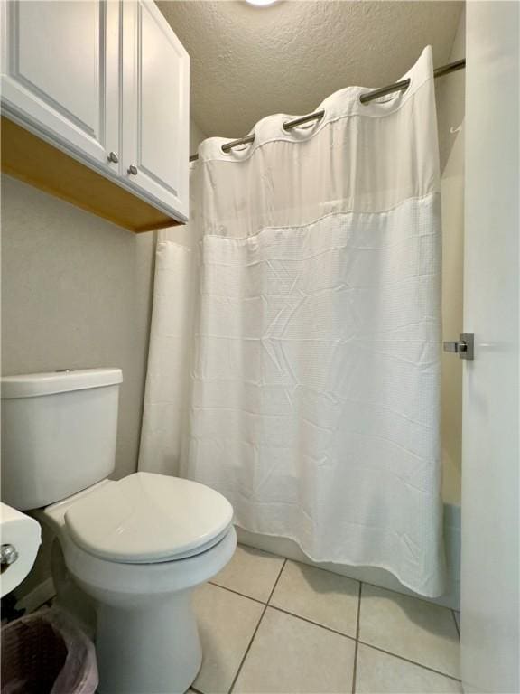 full bath featuring a textured ceiling, tile patterned flooring, and toilet