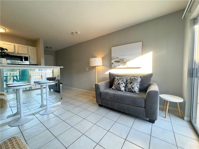 living room with a textured ceiling, light tile patterned flooring, and baseboards