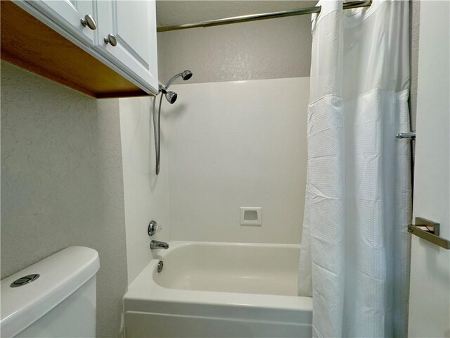 bathroom with toilet, shower / bath combination with curtain, and a textured wall