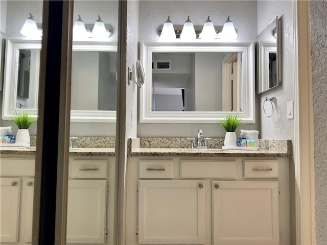 bathroom featuring vanity, visible vents, and a textured wall