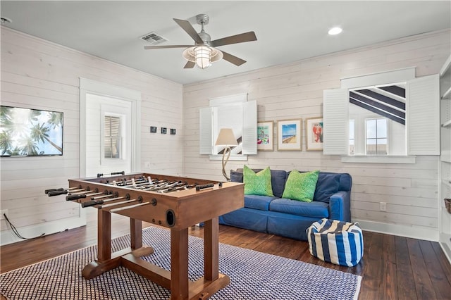 rec room with baseboards, visible vents, a ceiling fan, wood finished floors, and wood walls