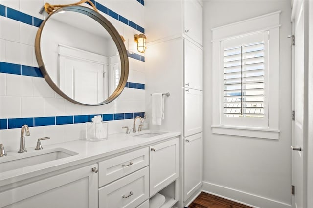 full bathroom featuring baseboards, double vanity, a sink, and decorative backsplash