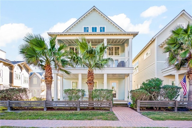 view of front of property featuring covered porch, a fenced front yard, and a balcony