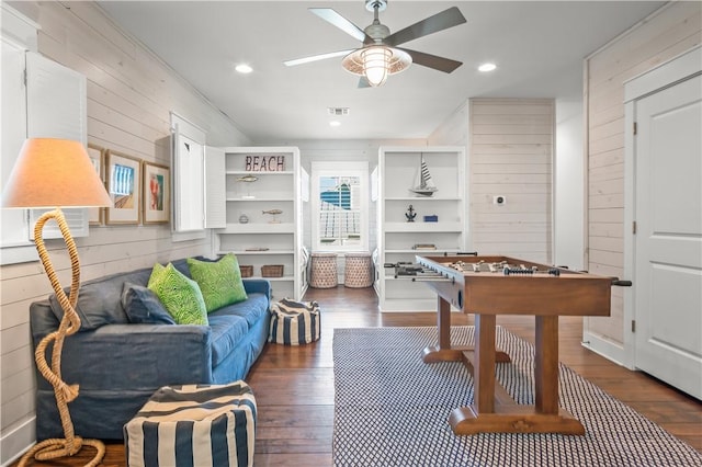 game room with dark wood-style flooring, recessed lighting, visible vents, wood walls, and ceiling fan