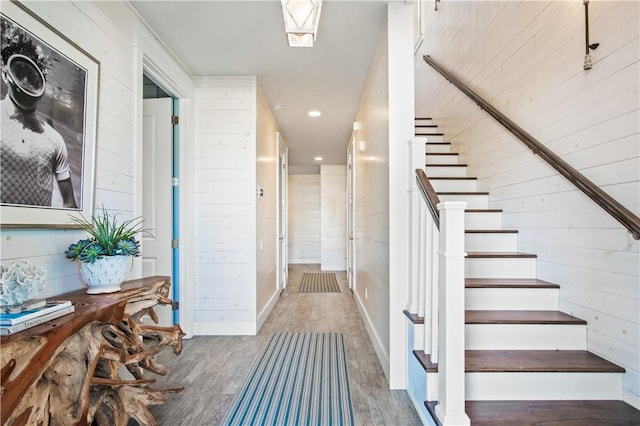 staircase with wooden walls and wood finished floors