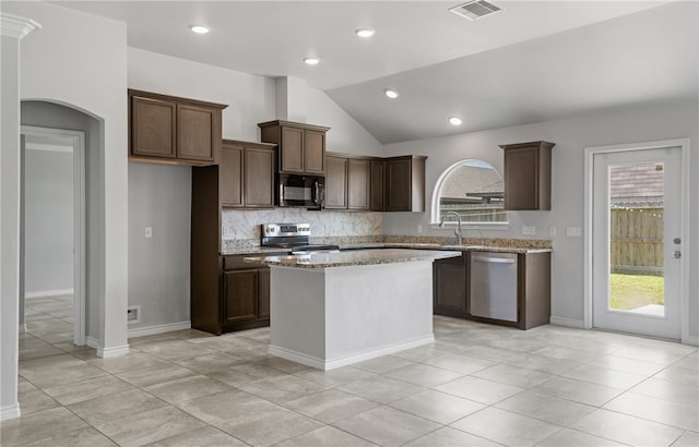 7525 Killebrew Dr, Corpus Christi, TX 78414 - kitchen with appliances with stainless steel finishes, lofted ceiling, backsplash, light stone counters, and a kitchen island