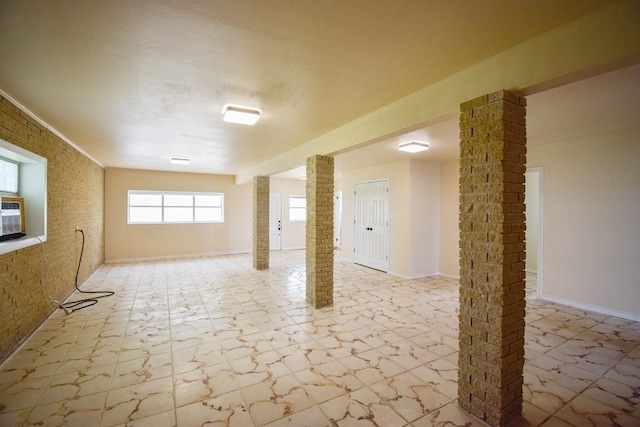 empty room featuring brick wall and decorative columns