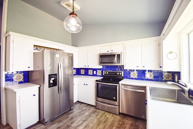 kitchen with sink, white cabinetry, decorative light fixtures, vaulted ceiling, and appliances with stainless steel finishes