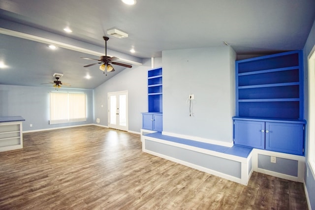 unfurnished living room featuring built in features, vaulted ceiling with beams, hardwood / wood-style flooring, ceiling fan, and french doors