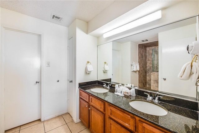 full bathroom featuring tile patterned floors, double vanity, and tiled shower