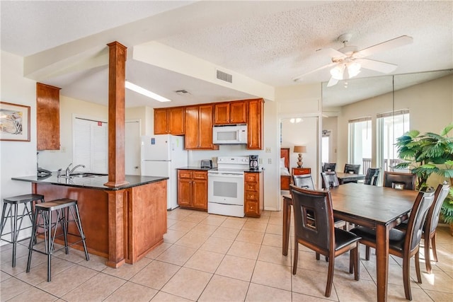 kitchen featuring white appliances, a peninsula, brown cabinets, ceiling fan, and a kitchen breakfast bar
