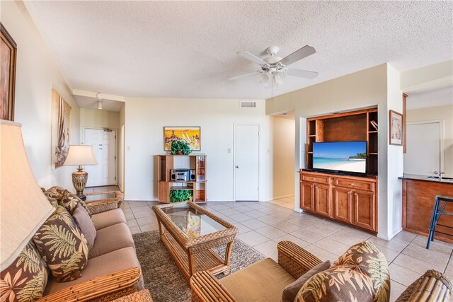 living room featuring light tile patterned flooring, ceiling fan, and a textured ceiling