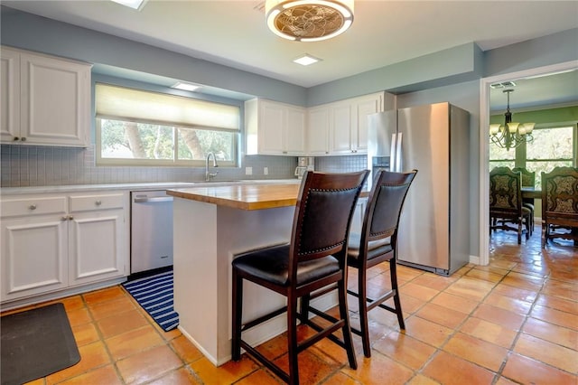 kitchen featuring backsplash, appliances with stainless steel finishes, a chandelier, and butcher block countertops