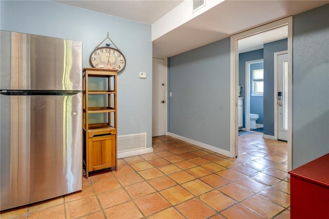 unfurnished dining area featuring baseboards, visible vents, and light tile patterned floors