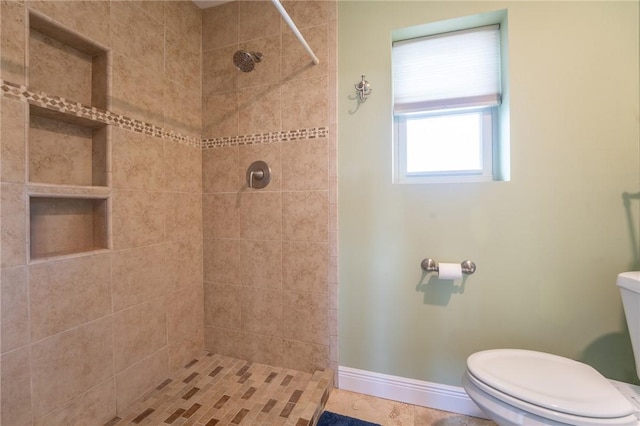 full bath featuring baseboards, toilet, and tiled shower
