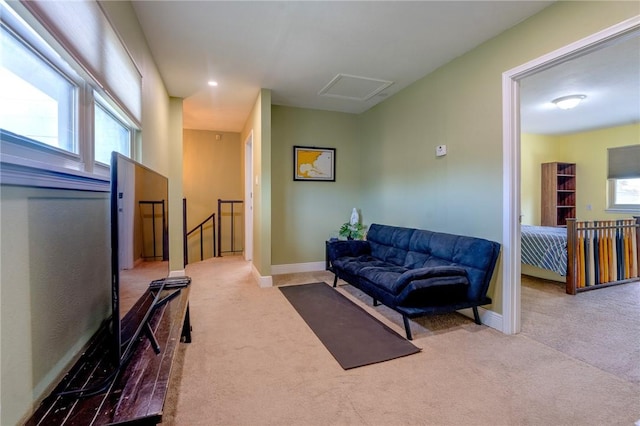 carpeted living area featuring attic access and baseboards