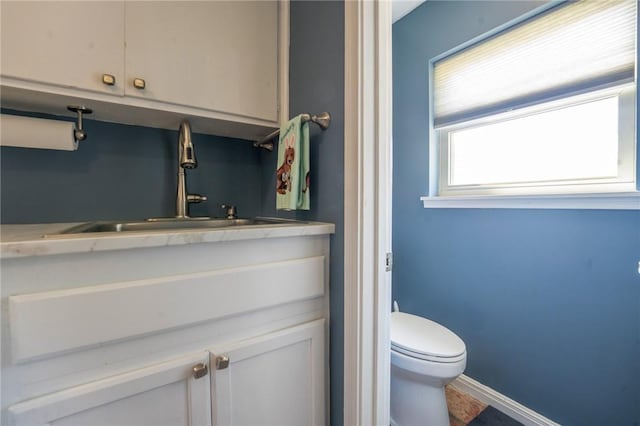 bathroom with toilet, vanity, and baseboards