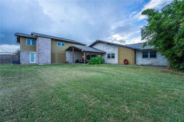 back of property featuring brick siding, central air condition unit, and a lawn