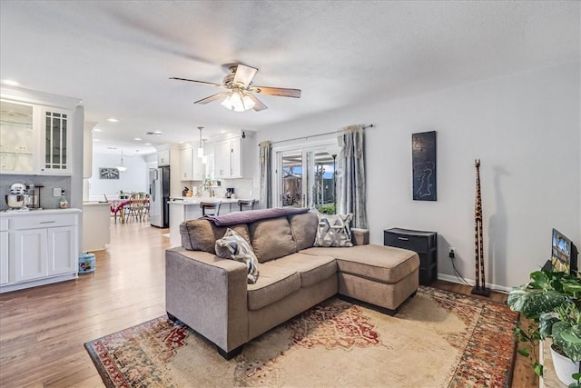 living room featuring a textured ceiling, ceiling fan, and light hardwood / wood-style flooring