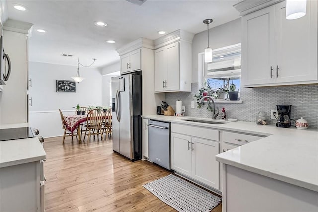 kitchen featuring sink, white cabinets, decorative light fixtures, and appliances with stainless steel finishes