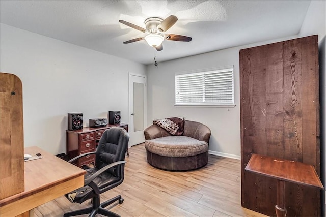 home office with ceiling fan, light hardwood / wood-style flooring, and a textured ceiling