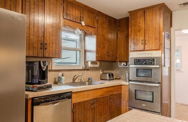 kitchen with decorative backsplash, sink, and stainless steel appliances