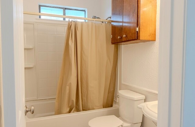 bathroom featuring shower / bath combination with curtain and toilet