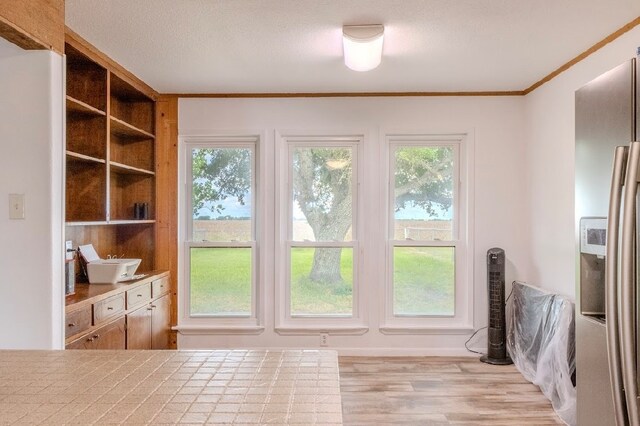 doorway to outside featuring a textured ceiling, light hardwood / wood-style floors, and crown molding